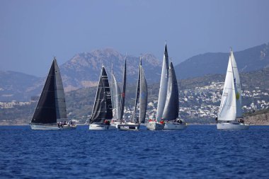 Bodrum, Hindi. 08 Mart 2025: Yelkenliler Ege Denizi 'nin mavi sularında, ünlü tatil beldesi Bodrum' un kıyılarında rüzgarlı havada yelken açıyorlar..