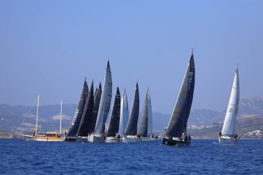 Bodrum, Hindi. 08 Mart 2025: Yelkenliler Ege Denizi 'nin mavi sularında, ünlü tatil beldesi Bodrum' un kıyılarında rüzgarlı havada yelken açıyorlar..
