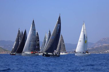 Bodrum, Hindi. 08 Mart 2025: Yelkenliler Ege Denizi 'nin mavi sularında, ünlü tatil beldesi Bodrum' un kıyılarında rüzgarlı havada yelken açıyorlar..