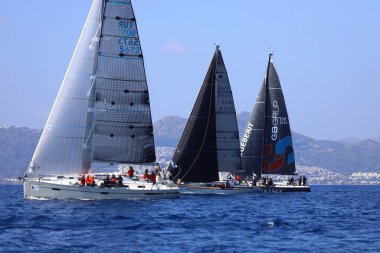 Bodrum, Hindi. 08 Mart 2025: Yelkenliler Ege Denizi 'nin mavi sularında, ünlü tatil beldesi Bodrum' un kıyılarında rüzgarlı havada yelken açıyorlar..