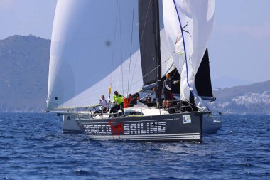 Bodrum, Hindi. 08 Mart 2025: Yelkenliler Ege Denizi 'nin mavi sularında, ünlü tatil beldesi Bodrum' un kıyılarında rüzgarlı havada yelken açıyorlar..