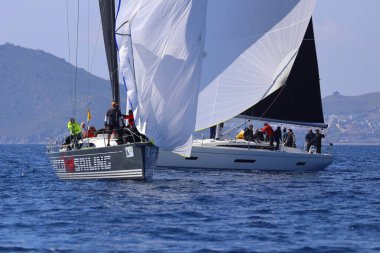 Bodrum, Hindi. 08 Mart 2025: Yelkenliler Ege Denizi 'nin mavi sularında, ünlü tatil beldesi Bodrum' un kıyılarında rüzgarlı havada yelken açıyorlar..