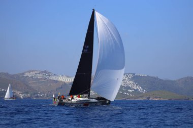 Bodrum, Hindi. 08 Mart 2025: Yelkenliler Ege Denizi 'nin mavi sularında, ünlü tatil beldesi Bodrum' un kıyılarında rüzgarlı havada yelken açıyorlar..