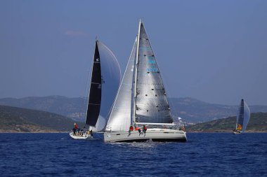 Bodrum, Hindi. 08 Mart 2025: Yelkenliler Ege Denizi 'nin mavi sularında, ünlü tatil beldesi Bodrum' un kıyılarında rüzgarlı havada yelken açıyorlar..