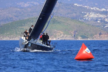 Bodrum, Hindi. 08 Mart 2025: Yelkenliler Ege Denizi 'nin mavi sularında, ünlü tatil beldesi Bodrum' un kıyılarında rüzgarlı havada yelken açıyorlar..