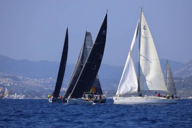 Bodrum, Hindi. 08 Mart 2025: Yelkenliler Ege Denizi 'nin mavi sularında, ünlü tatil beldesi Bodrum' un kıyılarında rüzgarlı havada yelken açıyorlar..