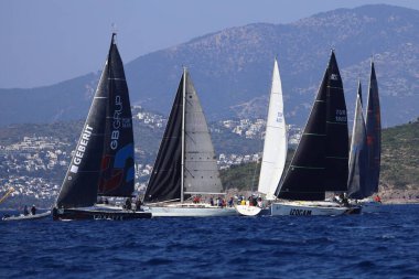 Bodrum, Hindi. 08 Mart 2025: Yelkenliler Ege Denizi 'nin mavi sularında, ünlü tatil beldesi Bodrum' un kıyılarında rüzgarlı havada yelken açıyorlar..