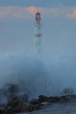 Eski deniz fenerinin üzerinde büyük fırtınalı bir dalga. Denizde fırtına, deniz fenerine çarpan dalgalar
