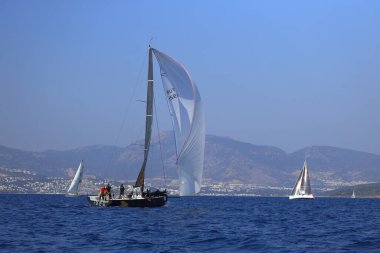Bodrum, Hindi. 08 Mart 2025: Yelkenliler Ege Denizi 'nin mavi sularında, ünlü tatil beldesi Bodrum' un kıyılarında rüzgarlı havada yelken açıyorlar..