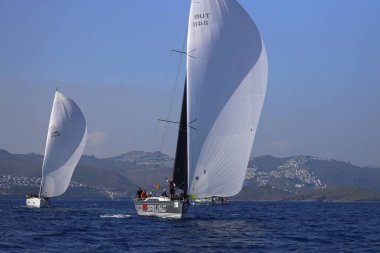 Bodrum, Hindi. 08 Mart 2025: Yelkenliler Ege Denizi 'nin mavi sularında, ünlü tatil beldesi Bodrum' un kıyılarında rüzgarlı havada yelken açıyorlar..