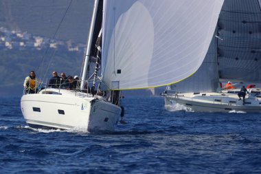 Bodrum, Hindi. 08 Mart 2025: Yelkenliler Ege Denizi 'nin mavi sularında, ünlü tatil beldesi Bodrum' un kıyılarında rüzgarlı havada yelken açıyorlar..