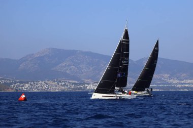 Bodrum, Hindi. 08 Mart 2025: Yelkenliler Ege Denizi 'nin mavi sularında, ünlü tatil beldesi Bodrum' un kıyılarında rüzgarlı havada yelken açıyorlar..