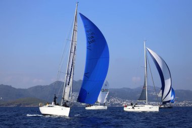 Bodrum, Hindi. 08 Mart 2025: Yelkenliler Ege Denizi 'nin mavi sularında, ünlü tatil beldesi Bodrum' un kıyılarında rüzgarlı havada yelken açıyorlar..