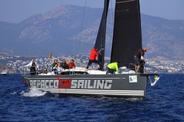Bodrum, Hindi. 08 Mart 2025: Yelkenliler Ege Denizi 'nin mavi sularında, ünlü tatil beldesi Bodrum' un kıyılarında rüzgarlı havada yelken açıyorlar..