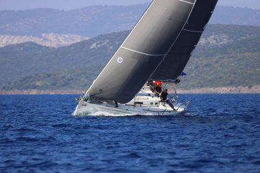 Bodrum, Hindi. 08 Mart 2025: Yelkenliler Ege Denizi 'nin mavi sularında, ünlü tatil beldesi Bodrum' un kıyılarında rüzgarlı havada yelken açıyorlar..