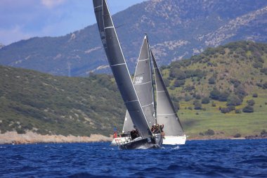 Bodrum, Hindi. 06 Nisan 2025: Ege Denizi 'nin mavi sularında, ünlü tatil beldesi Bodrum' un kıyılarında yelkenliler rüzgarlı havada yelken açıyor.
