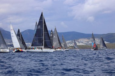 Bodrum, Hindi. 06 Nisan 2025: Ege Denizi 'nin mavi sularında, ünlü tatil beldesi Bodrum' un kıyılarında yelkenliler rüzgarlı havada yelken açıyor.