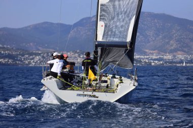 Bodrum, Hindi. 26 Nisan 2025: Yelkenliler Ege Denizi 'nin mavi sularında, ünlü tatil beldesi Bodrum' un kıyılarında rüzgarlı havada yelken açıyor..