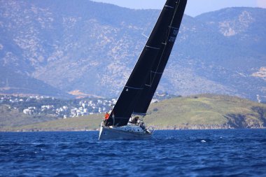 Bodrum, Hindi. 26 Nisan 2025: Yelkenliler Ege Denizi 'nin mavi sularında, ünlü tatil beldesi Bodrum' un kıyılarında rüzgarlı havada yelken açıyor..