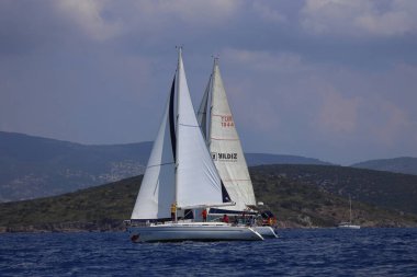 Bodrum, Hindi. 27 Nisan 2025: Ege Denizi 'nin mavi sularında, ünlü tatil beldesi Bodrum' un kıyılarında yelkenliler rüzgarlı havada yelken açıyor.