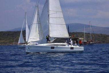 Bodrum, Hindi. 27 Nisan 2025: Ege Denizi 'nin mavi sularında, ünlü tatil beldesi Bodrum' un kıyılarında yelkenliler rüzgarlı havada yelken açıyor.