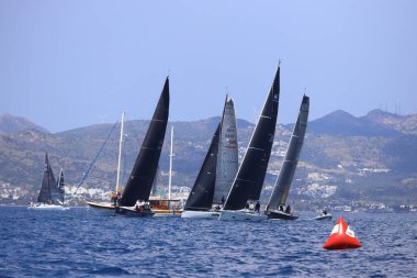 Bodrum, Hindi. 27 Nisan 2025: Ege Denizi 'nin mavi sularında, ünlü tatil beldesi Bodrum' un kıyılarında yelkenliler rüzgarlı havada yelken açıyor.