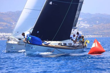 Bodrum, Hindi. 27 Nisan 2025: Ege Denizi 'nin mavi sularında, ünlü tatil beldesi Bodrum' un kıyılarında yelkenliler rüzgarlı havada yelken açıyor.