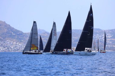 Bodrum, Hindi. 27 Nisan 2025: Ege Denizi 'nin mavi sularında, ünlü tatil beldesi Bodrum' un kıyılarında yelkenliler rüzgarlı havada yelken açıyor.