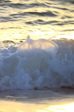 Gün batımında dalga sıçraması. Okyanus suyu gün ışığında hareket halinde. Soyut deniz arkaplanı