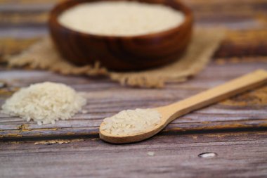 Siyah arka planda çiğ beyaz pirinç. Ahşap tabakta uzun pişmemiş pirinç. Doğal organik gıda. Geleneksel Asya mısır gevreği kültürü.