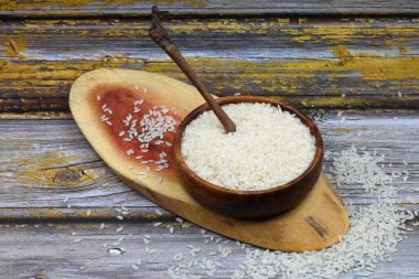 Siyah arka planda çiğ beyaz pirinç. Ahşap tabakta uzun pişmemiş pirinç. Doğal organik gıda. Geleneksel Asya mısır gevreği kültürü.