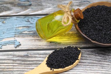 Siyah kimyon tohumları ve kase, tahta kürek ya da kaşık ile gerekli yağ. Nigella Sativa cam şişede. Birçok hastalık için organik bitkisel ilaç