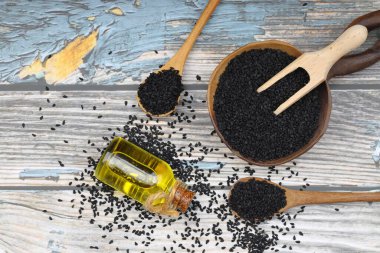 Siyah kimyon tohumları ve kase, tahta kürek ya da kaşık ile gerekli yağ. Nigella Sativa cam şişede. Birçok hastalık için organik bitkisel ilaç