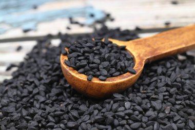 Siyah kimyon tohumları ve kase, tahta kürek ya da kaşık ile gerekli yağ. Nigella Sativa cam şişede. Birçok hastalık için organik bitkisel ilaç