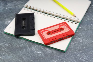 80 'lerden ve 90' lardan kalma kaset kaydı beyaz bir arkaplanda. Defterde boş çalma listesi. Üst görüş, nostaljik konsept.