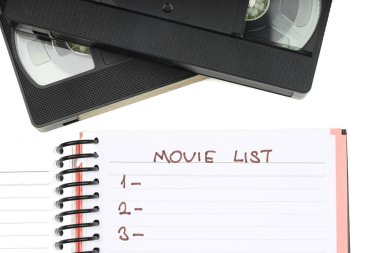 Beyaz arkaplanda boş etiketli siyah VHS video kaset. Ve boş film listesi.