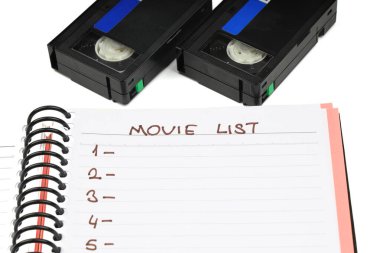 Beyaz arkaplanda boş etiketli siyah VHS video kaset. Ve boş film listesi.