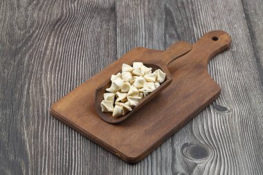 Ahşap kepçe üzerinde el yapımı manti (Türkçe ravioli tipi hamur tatlısı), pişirmeden önce