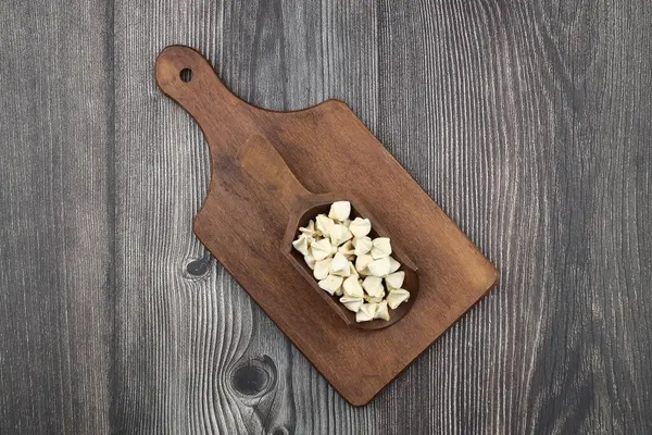 Ahşap kepçe üzerinde el yapımı manti (Türkçe ravioli tipi hamur tatlısı), pişirmeden önce