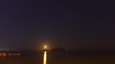 Gökyüzü karardıkça, adanın arkasında yeni ay batar..