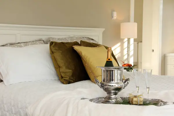 Flasche Champagner Auf Eis Auf Einem Luxuriösen Bett Romantisches Hotelzimmer lizenzfreie Stockfotos