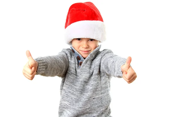 Netter Fünfjähriger Junge Mit Weihnachtsmütze Und Zwei Daumen Hoch lizenzfreie Stockfotos