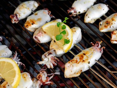 Kömür ızgarasında taze ızgara kalamar şiş, limon ve taze kekik, lezzetli ızgara deniz ürünleri..
