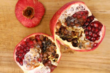 Halved moldy pomegranate on a wooden cutting board, mold on fruit can be harmful to health. clipart