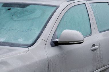 Soğuk bir kış gününde, buz kristalleriyle kaplı gri bir arabanın donmuş camları..