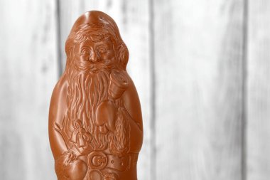 Beyaz rustik ahşap arkaplan ve fotokopi alanı olan paketlenmemiş çikolatalı Noel Baba 'nın kapağını kapat..