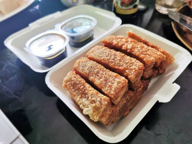 Fırınlanmış ve kızarmış domuz eti ürünleri cam masanın üzerindeki beyaz bir karton kutuya konmuş.