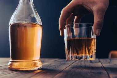 Yakından bir şişe viski ve bardak tutan iş adamları.