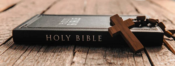wooden cross on Bible on wooden tabl