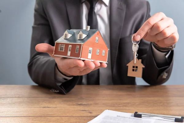 Real estate agent handing over house keys in han